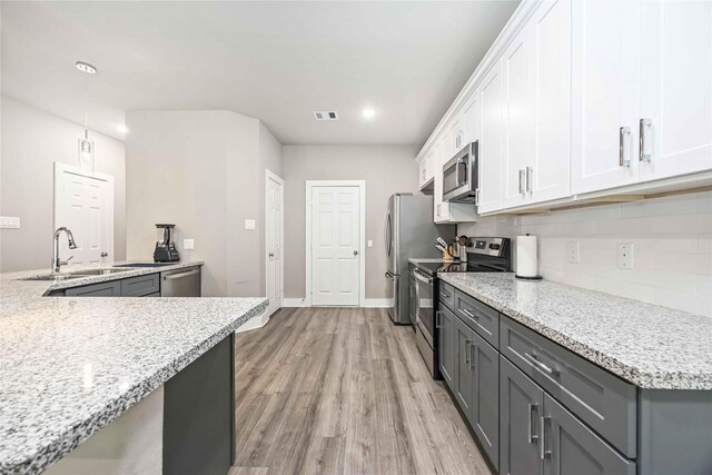 5023 Mallow St A/B, Unit A/B Houston, TX 77033 - kitchen with appliances with stainless steel finishes, a sink, tasteful backsplash, light wood finished floors, and white cabinets
