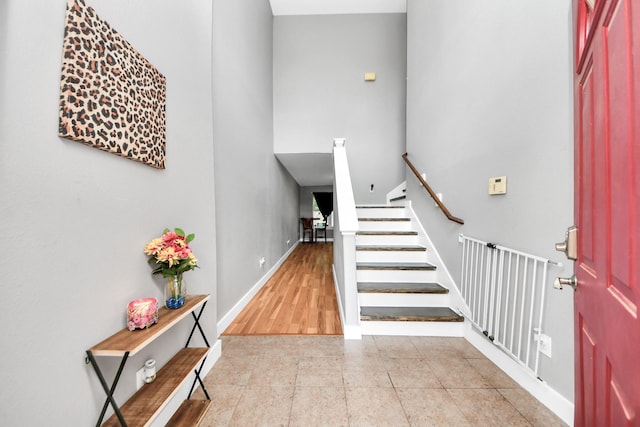 entryway with baseboards, stairway, tile patterned flooring, and a high ceiling
