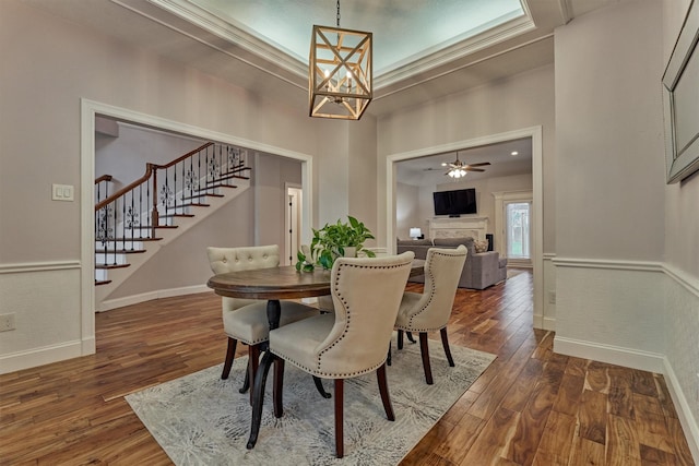 dining space featuring stairway, a chandelier, dark wood finished floors, and a fireplace