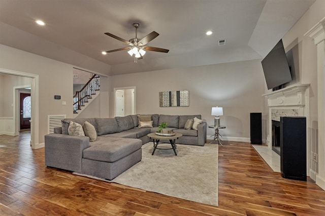 living room featuring wood finished floors, stairs, a fireplace, ceiling fan, and baseboards