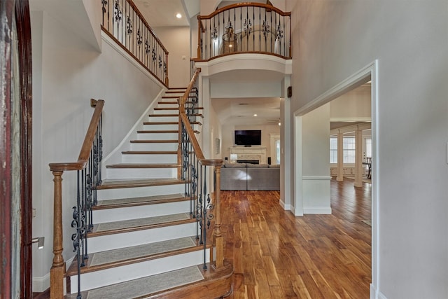 entrance foyer with a high ceiling, a fireplace, wood finished floors, baseboards, and stairs