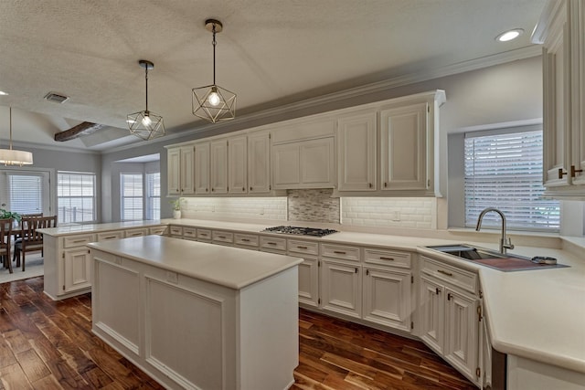 kitchen with stainless steel gas stovetop, a peninsula, dark wood-type flooring, light countertops, and a textured ceiling