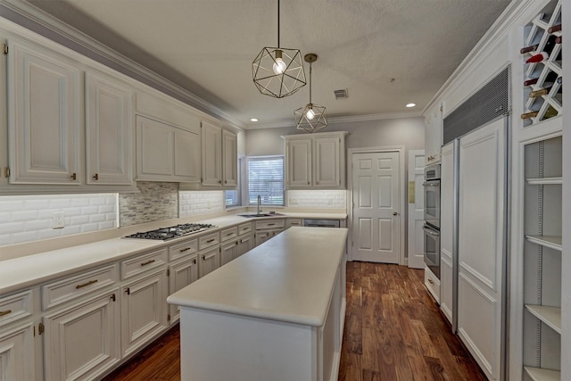 kitchen featuring stainless steel appliances, a sink, tasteful backsplash, a kitchen island, and light countertops