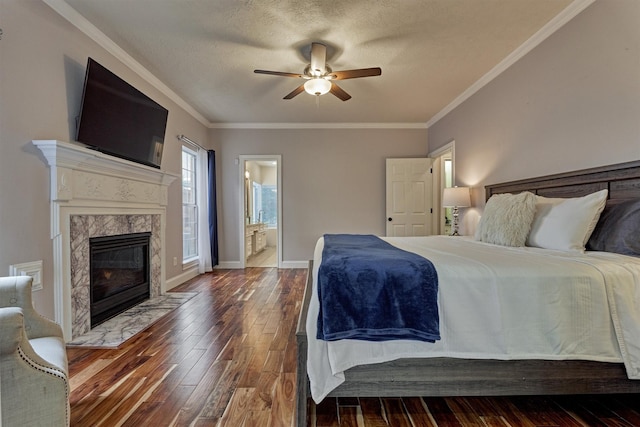 bedroom featuring hardwood / wood-style flooring, a high end fireplace, ornamental molding, ensuite bath, and a ceiling fan