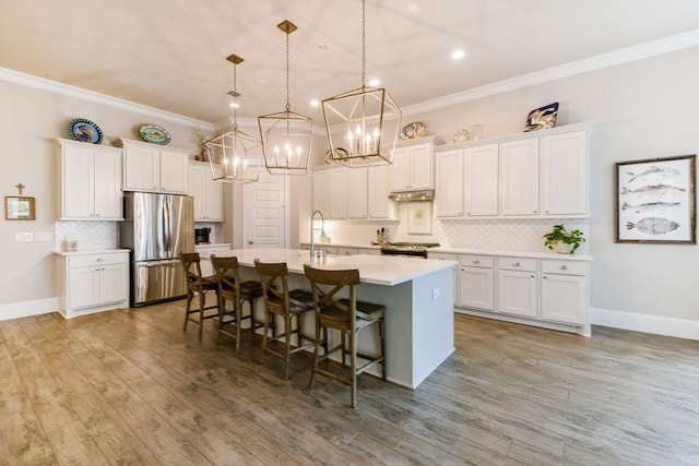 2176 Rope Maker Rd, Conroe, TX 77384 - kitchen with appliances with stainless steel finishes, a chandelier, an island with sink, decorative backsplash, and light countertops