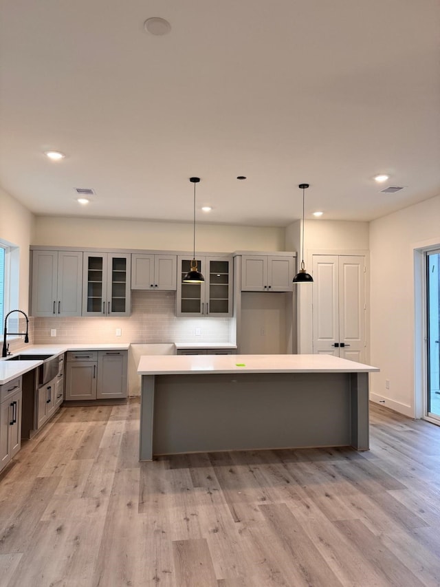 2708 Nagle St, Houston, TX 77004 - kitchen with gray cabinetry, a sink, tasteful backsplash, glass insert cabinets, and recessed lighting