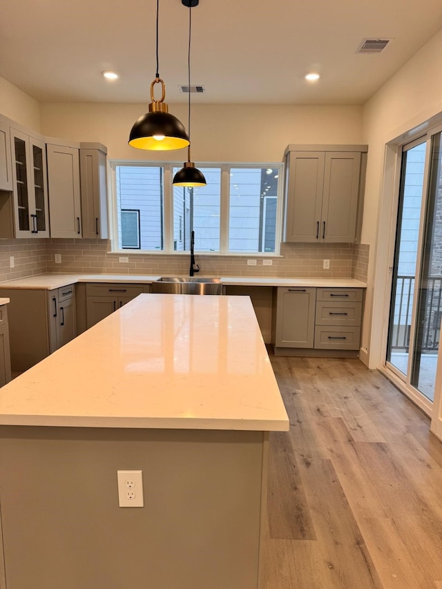 2708 Nagle St, Houston, TX 77004 - kitchen featuring gray cabinets, backsplash, recessed lighting, light wood-type flooring, and glass insert cabinets
