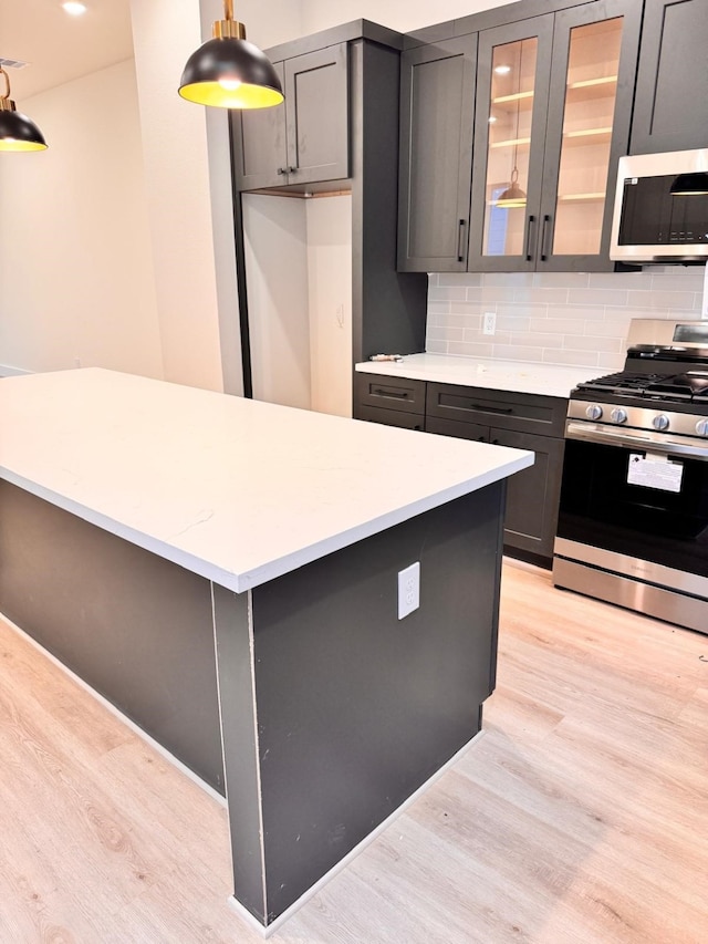 2708 Nagle St, Houston, TX 77004 - kitchen featuring stainless steel appliances, light wood-type flooring, gray cabinetry, and decorative backsplash