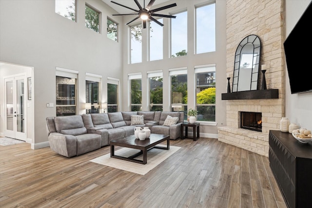 321 Waterford Way, Montgomery, TX 77356 - living room with a ceiling fan, wood finished floors, a towering ceiling, a stone fireplace, and baseboards