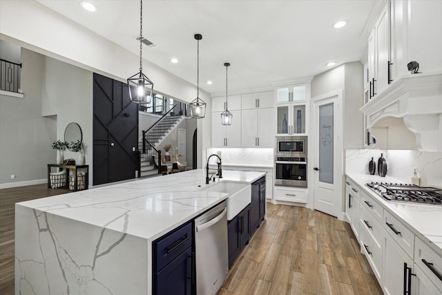 321 Waterford Way, Montgomery, TX 77356 - kitchen with appliances with stainless steel finishes, a sink, blue cabinets, light wood-type flooring, and decorative backsplash