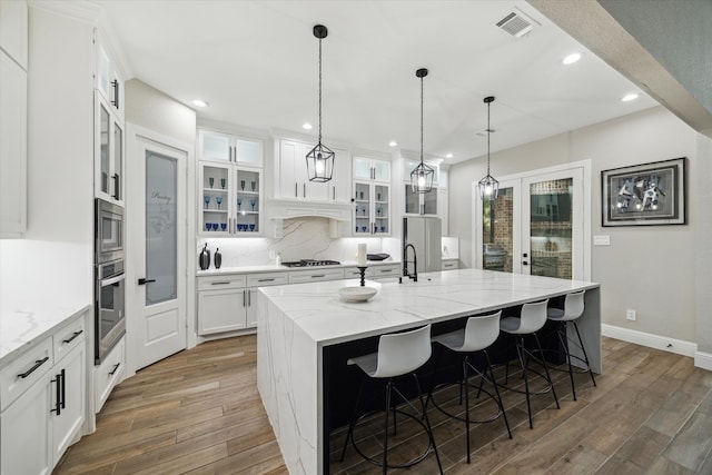 321 Waterford Way, Montgomery, TX 77356 - kitchen with stainless steel appliances, light wood finished floors, a center island with sink, white cabinetry, and recessed lighting