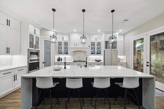 321 Waterford Way, Montgomery, TX 77356 - kitchen with stainless steel appliances, decorative backsplash, a large island with sink, dark wood-style flooring, and white cabinets