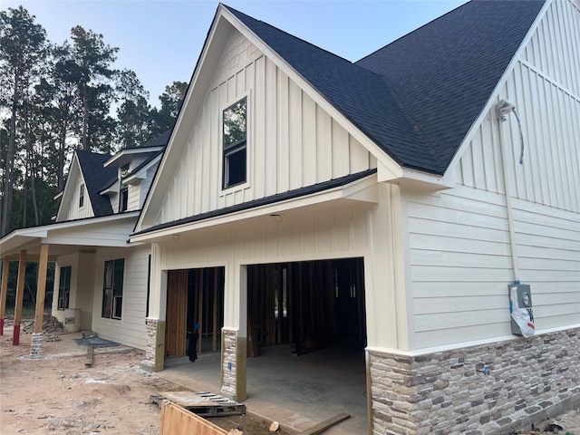 124 Hickory, Village Mills, TX 77663 - view of side of home with roof with shingles, board and batten siding, an attached garage, and stone siding