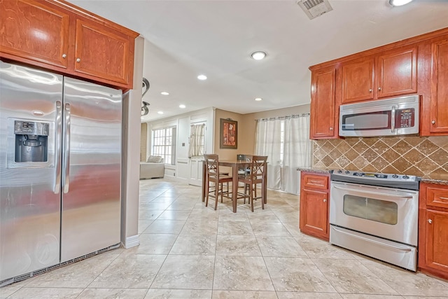 711 Lodgehill Ln, Houston, TX 77090 - kitchen with appliances with stainless steel finishes, recessed lighting, decorative backsplash, brown cabinetry, and light tile patterned floors