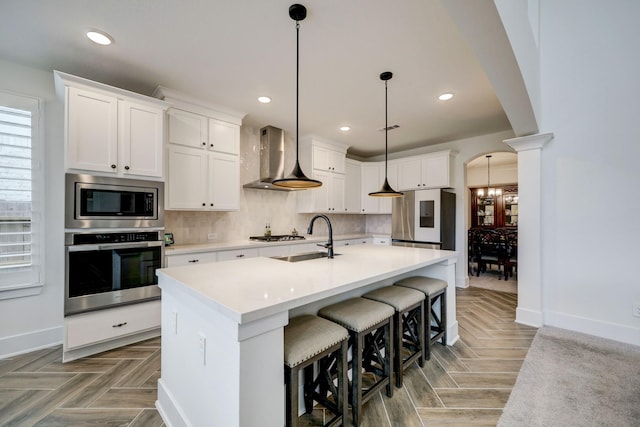 12531 Tullich Run Dr, Humble, TX 77346 - kitchen featuring appliances with stainless steel finishes, wall chimney range hood, a sink, baseboards, and recessed lighting