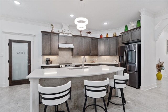 1314 Briar Cliff St, Conroe, TX 77385 - kitchen with appliances with stainless steel finishes, under cabinet range hood, dark brown cabinets, a breakfast bar, and a sink