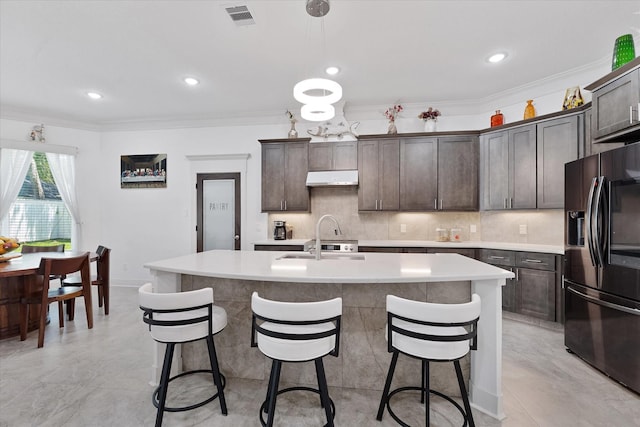 1314 Briar Cliff St, Conroe, TX 77385 - kitchen featuring black refrigerator with ice dispenser, under cabinet range hood, a sink, dark brown cabinets, and light countertops