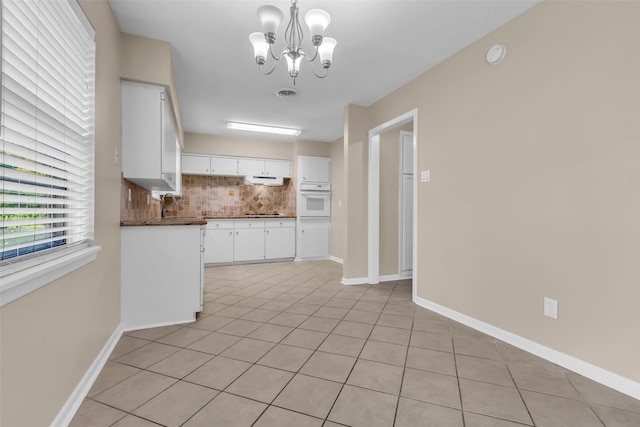 5839 Ettrick Dr, Houston, TX 77035 - kitchen with white oven, backsplash, dark countertops, white cabinetry, and a chandelier