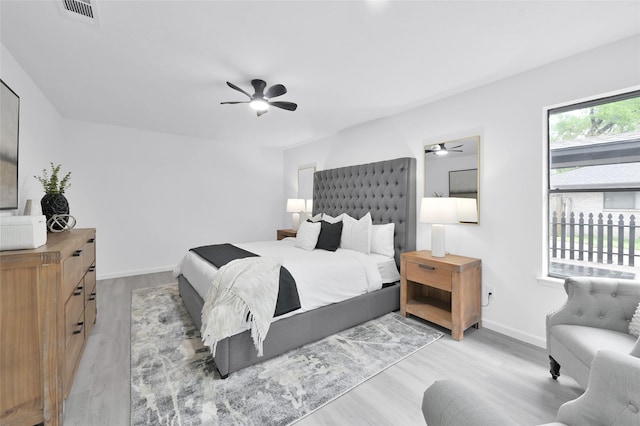 bedroom with light wood-type flooring, a ceiling fan, and baseboards