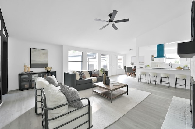 living area featuring light wood-type flooring, healthy amount of natural light, a ceiling fan, and high vaulted ceiling