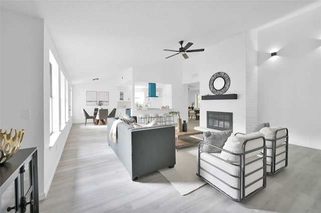 living area with wood finished floors, ceiling fan, high vaulted ceiling, a fireplace, and baseboards