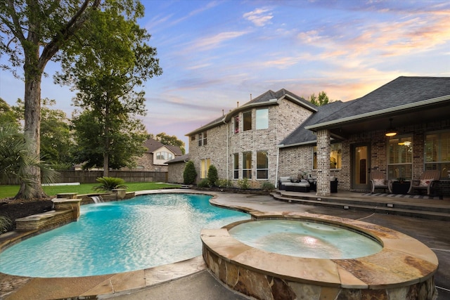 10114 Logan Grove Ct, Conroe, TX 77302 - pool at dusk featuring a fenced backyard, a patio area, and a pool with connected hot tub