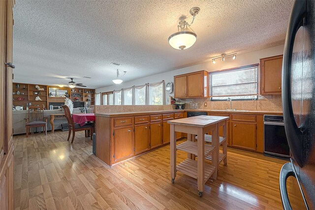 220 Hillcrest Dr, Coldspring, TX 77331 - kitchen with a peninsula, black appliances, healthy amount of natural light, brown cabinetry, and a textured ceiling