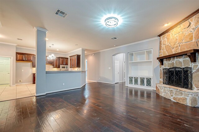 18306 S Austin Shore Dr, Cypress, TX 77433 - unfurnished living room with hardwood / wood-style flooring, ornamental molding, arched walkways, a stone fireplace, and baseboards