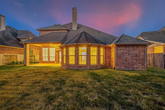 18306 S Austin Shore Dr, Cypress, TX 77433 - back of house at dusk featuring brick siding, a patio area, a chimney, and roof with shingles