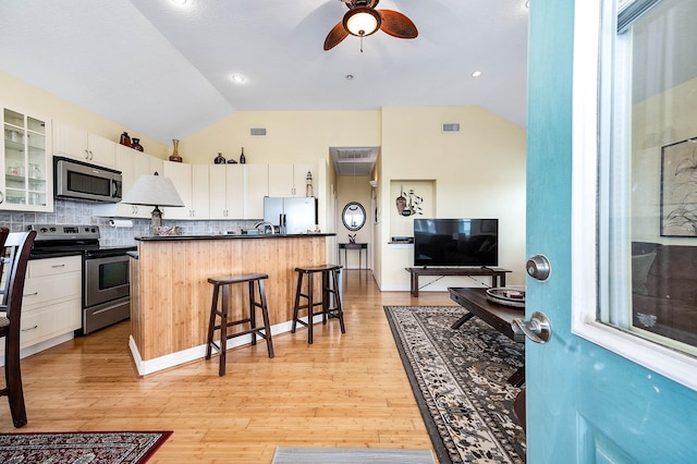 171 County Road 299, Sargent, TX 77414 - kitchen with stainless steel appliances, lofted ceiling, dark countertops, a kitchen bar, and decorative backsplash