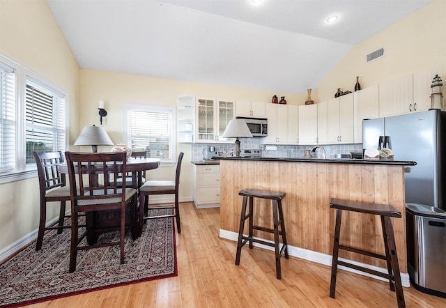171 County Road 299, Sargent, TX 77414 - kitchen featuring stainless steel appliances, vaulted ceiling, dark countertops, a kitchen breakfast bar, and light wood-style floors