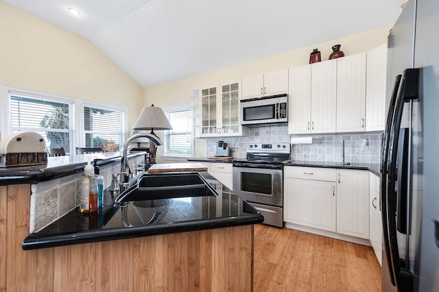 171 County Road 299, Sargent, TX 77414 - kitchen featuring stainless steel appliances, a sink, lofted ceiling, decorative backsplash, and glass insert cabinets