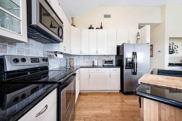 171 County Road 299, Sargent, TX 77414 - kitchen with appliances with stainless steel finishes, lofted ceiling, light wood finished floors, tasteful backsplash, and glass insert cabinets