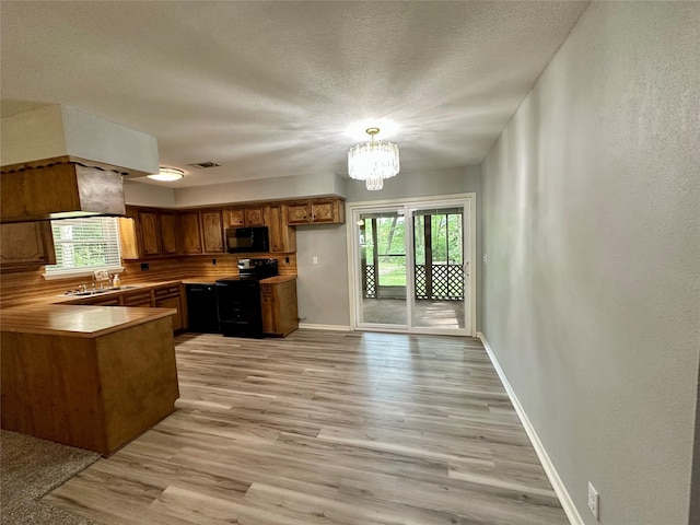 202 Spring Creek Loop, Livingston, TX 77351 - kitchen with black appliances, a sink, a peninsula, healthy amount of natural light, and a textured wall
