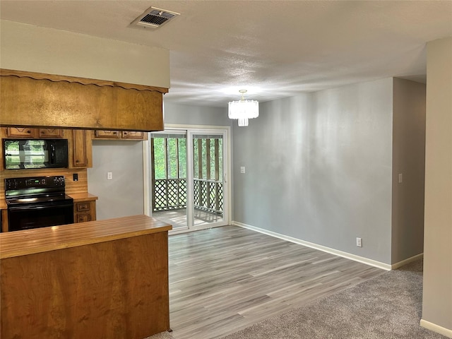 202 Spring Creek Loop, Livingston, TX 77351 - kitchen with black appliances, brown cabinets, a chandelier, baseboards, and butcher block counters