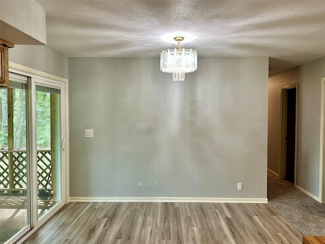 202 Spring Creek Loop, Livingston, TX 77351 - unfurnished dining area featuring wood finished floors, a textured ceiling, a chandelier, and baseboards