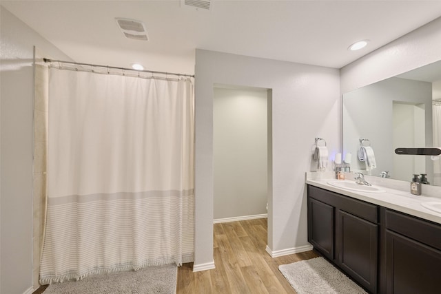 16953 Rich Pines Dr, Conroe, TX 77302 - bathroom featuring wood finished floors, double vanity, a shower with shower curtain, and baseboards