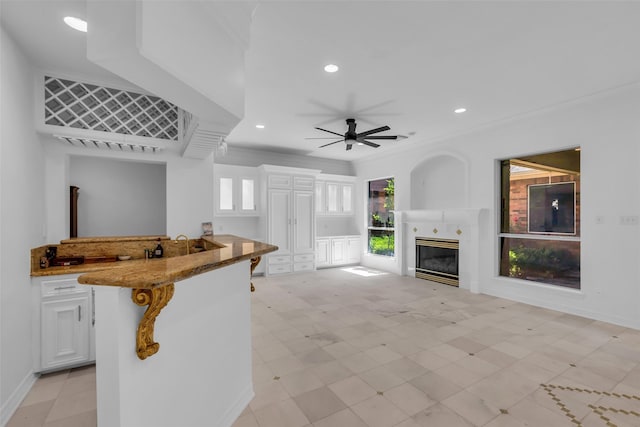 24 Stonegate Park Ct, Spring, TX 77379 - kitchen featuring stone countertops, white cabinetry, a fireplace, ceiling fan, and crown molding
