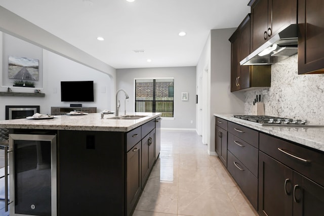 6706 Miller Shadow Ln, Sugar Land, TX 77479 - kitchen with a sink, under cabinet range hood, stainless steel gas cooktop, decorative backsplash, and dark brown cabinets