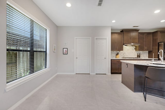 6706 Miller Shadow Ln, Sugar Land, TX 77479 - kitchen featuring healthy amount of natural light, under cabinet range hood, decorative backsplash, stainless steel gas cooktop, and recessed lighting