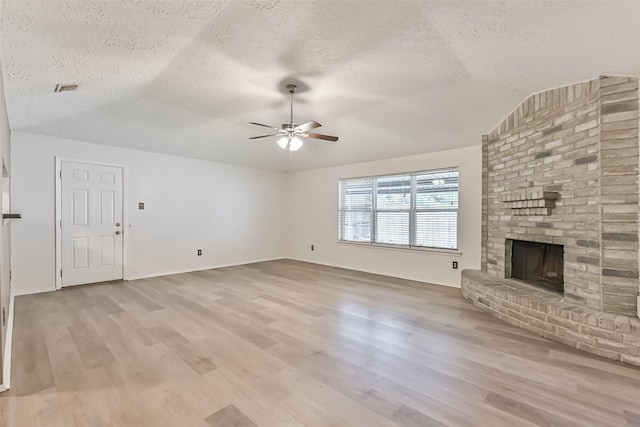 3915 Rosemont Dr, La Porte, TX 77571 - unfurnished living room with a textured ceiling, vaulted ceiling, ceiling fan, light wood-style floors, and a brick fireplace