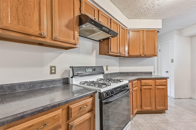 3915 Rosemont Dr, La Porte, TX 77571 - kitchen with gas stove, under cabinet range hood, dark countertops, light tile patterned floors, and a textured ceiling