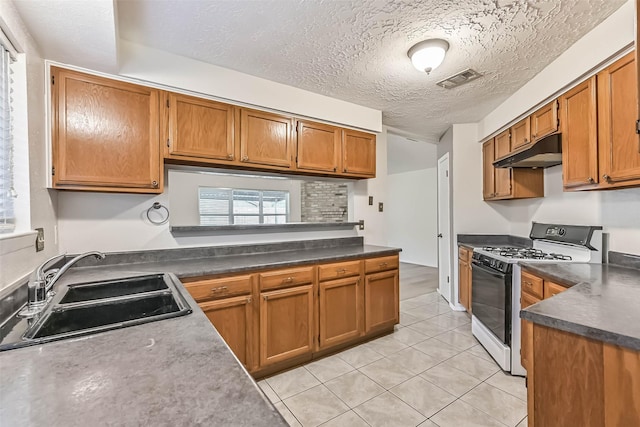 3915 Rosemont Dr, La Porte, TX 77571 - kitchen featuring gas range, under cabinet range hood, a sink, brown cabinetry, and a textured ceiling