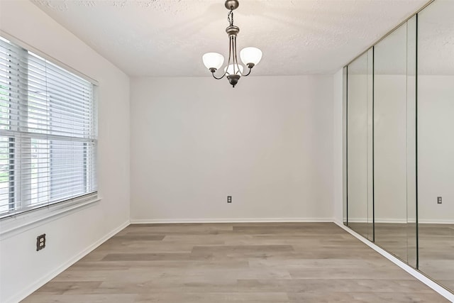 3915 Rosemont Dr, La Porte, TX 77571 - unfurnished dining area with healthy amount of natural light, a chandelier, a textured ceiling, light wood-type flooring, and baseboards