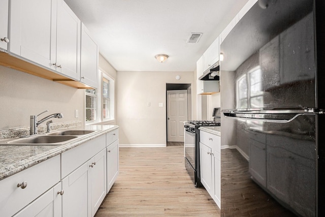 7306 Lakewood Dr, Houston, TX 77016 - kitchen featuring black appliances, under cabinet range hood, a sink, light wood finished floors, and white cabinets