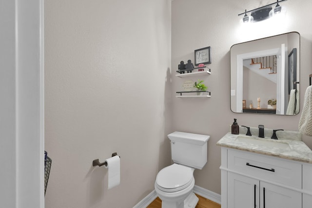 bathroom featuring toilet, vanity, wood finished floors, and baseboards