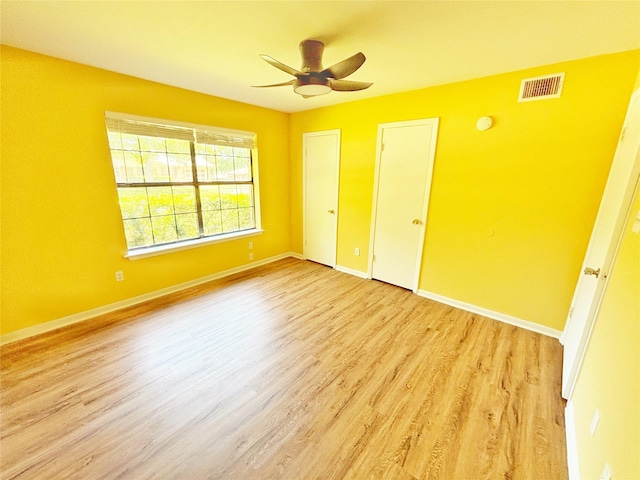 803 Wolley Cir, Crockett, TX 75835 - unfurnished bedroom featuring wood finished floors, baseboards, a ceiling fan, and two closets