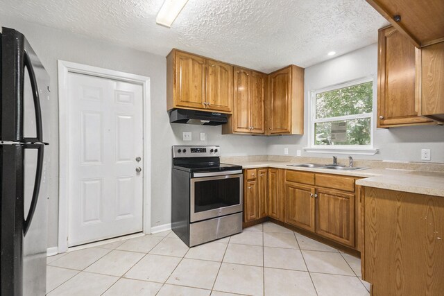 2705 Camille St, Pasadena, TX 77506 - kitchen featuring stainless steel range with electric cooktop, freestanding refrigerator, under cabinet range hood, a sink, and brown cabinets