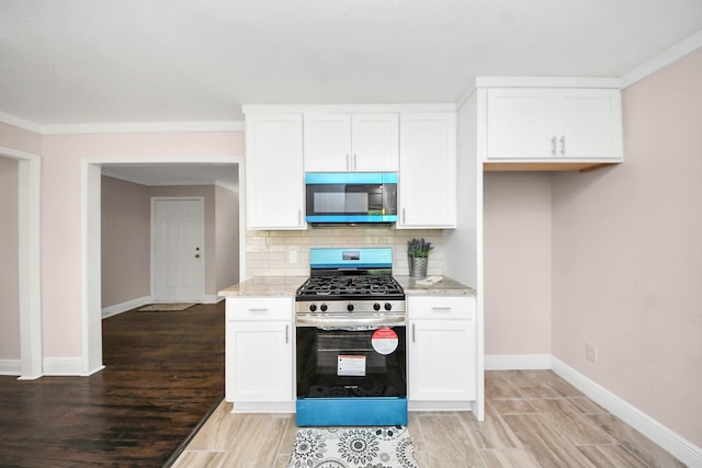 129 E 6th St, Deer Park, TX 77536 - kitchen with stainless steel range with gas stovetop, baseboards, white cabinetry, and tasteful backsplash