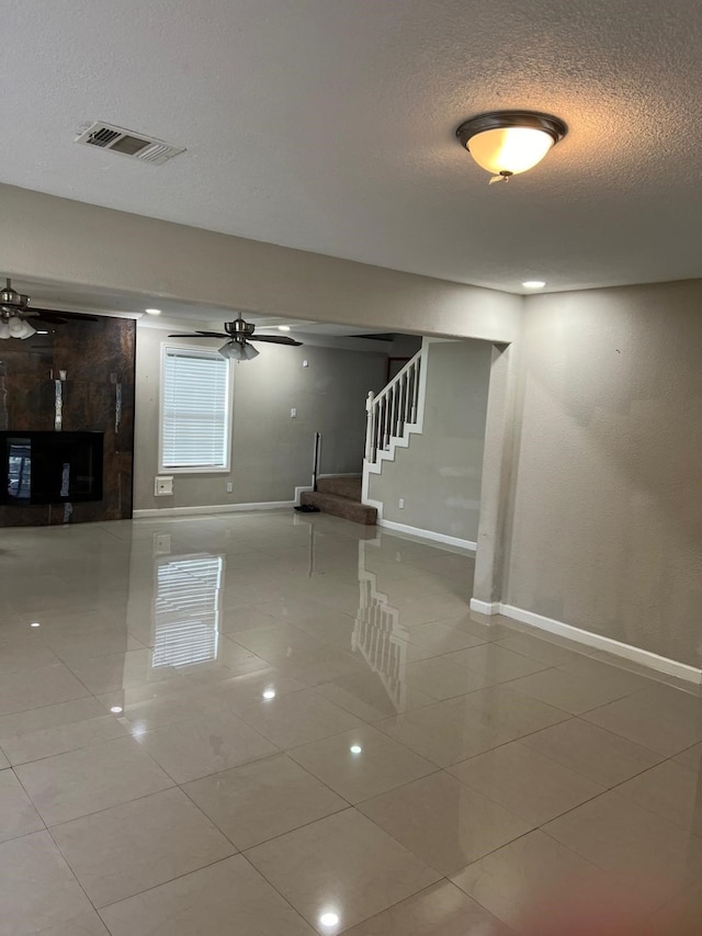 1506 Grand Valley Dr, Houston, TX 77090 - empty room with baseboards, ceiling fan, a textured ceiling, tile patterned floors, and a large fireplace
